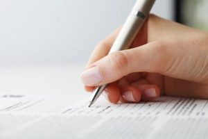 Businesswoman's hand with pen completing personal information on a form